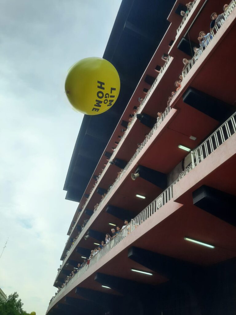 Lim Go Home balloon floats above the heads of protesters below the famous balconies of the grand old Mestalla
